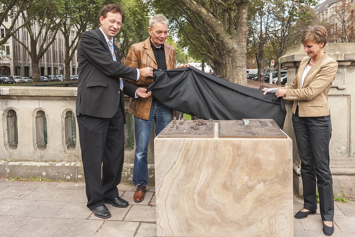 Burkhard Hintzsche (Stadt Düsseldorf), Gerd Kozyk (Allg. Blindenverein Düsseldorf e. V.) und Eva-Maria Illigen-Günther (Tourismus-GmbH) enthüllen den Stadtplan an der Kö. Düsseldorf Marketing & Tourismus GmbH