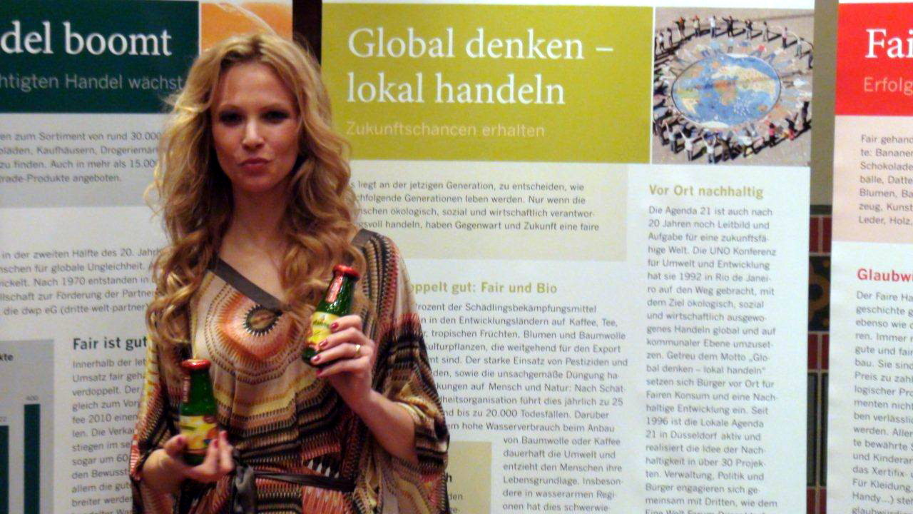 Birte Glang, Moderatorin der Fair Fashion`s Night, posiert vor Fairtrade-Plakaten. Benedikt Sondermann