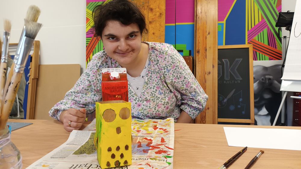 Christina (23) bastelt eine gelbe Eulen-Laterne aus einer Milchtüte.