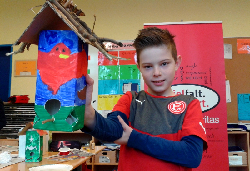 Nils (10) zeigt stolz das Futterhäuschen, das er in der Projektwoche gebaut hat. jt