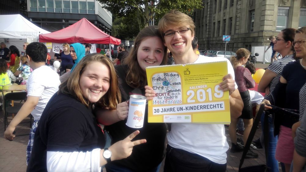 Sina Jansen, Vanessa Jansen und Niklas Kroh präsentieren den Jugendrat-Kinderrechtekalender auf dem Kinderfest zum Weltkindertag